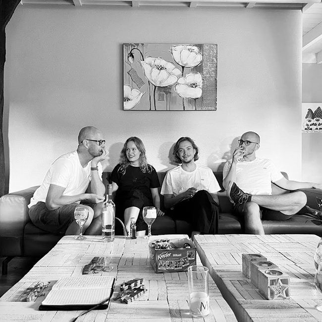 Vier Personen aus dem Team sitzen zusammen auf der Couch und unterhalten sich