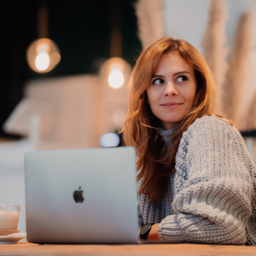 Eine Frau, die vor einem MacBook sitzt.