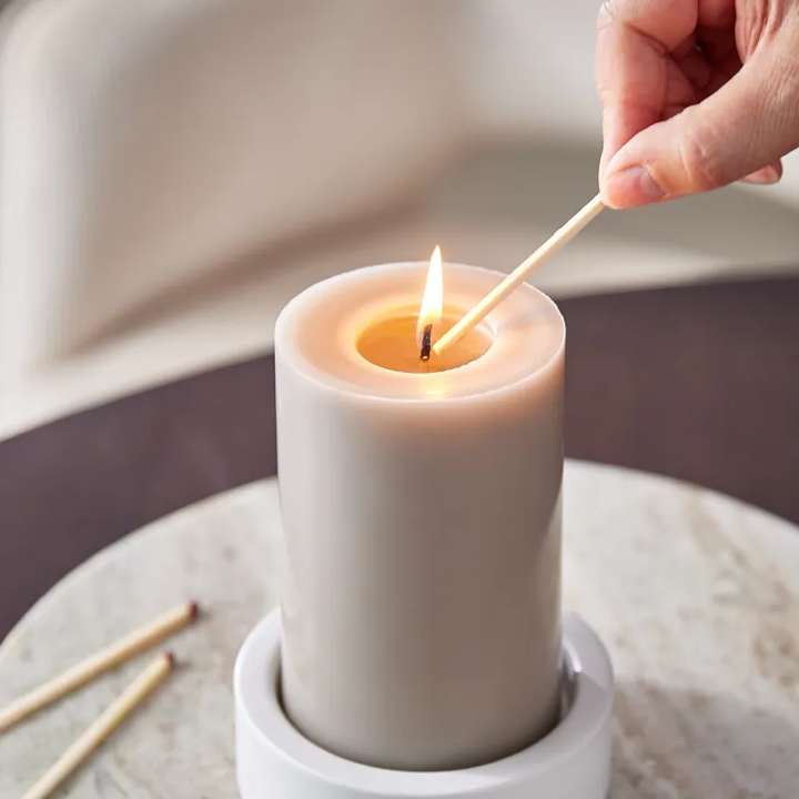 Eine Kerze wird von einem Streichholz angezündet.