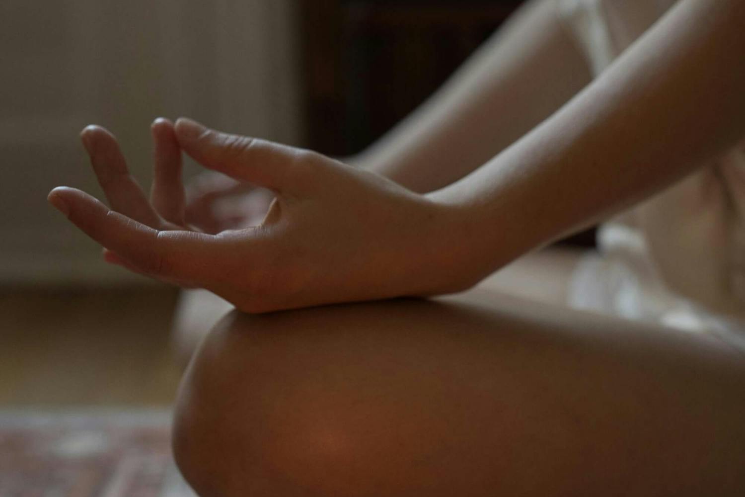 Frau sitzt im Schneidersitz vor einer Kerze Frau sitzt im Schneidersitz vor einer Kerze