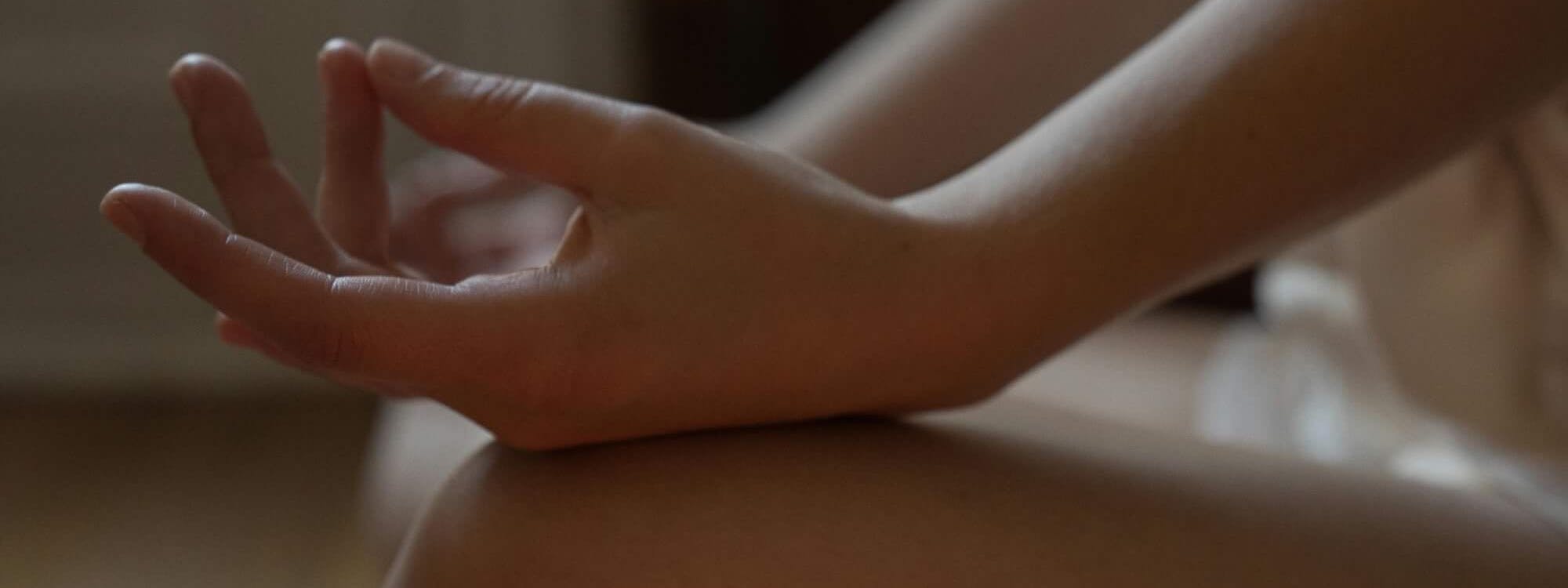 Frau sitzt im Schneidersitz vor einer Kerze