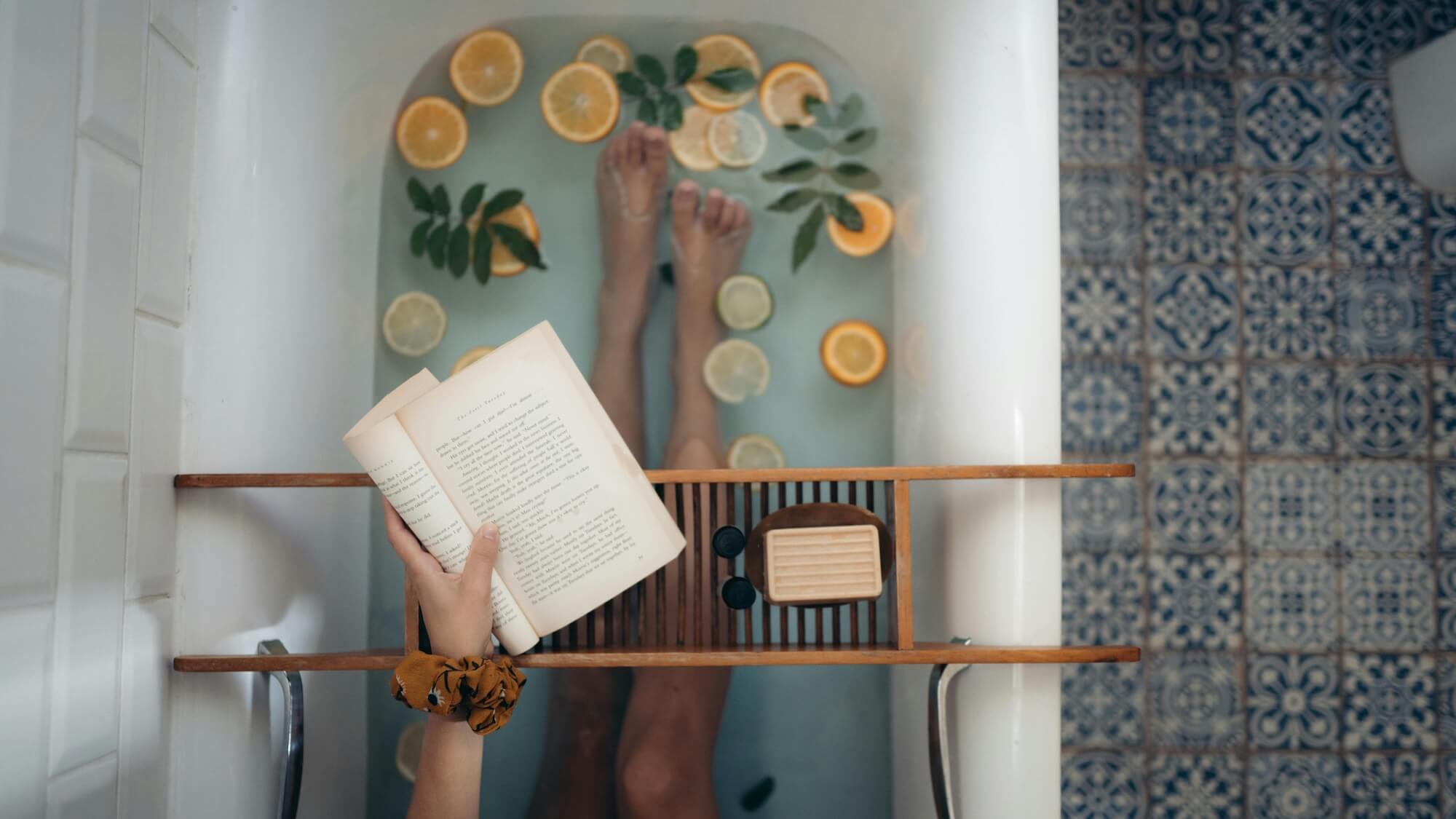 Frau sitzt mit Buch in Badewanne