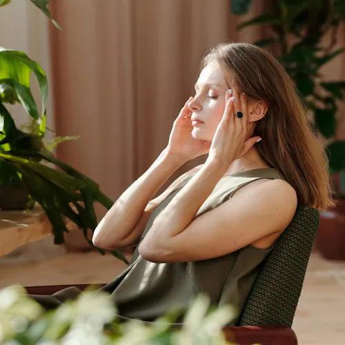 Frau sitzt am Tisch mit Kopfschmerzen