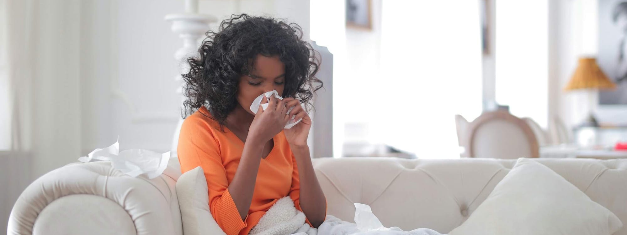 Frau liegt erkältet auf dem Sofa