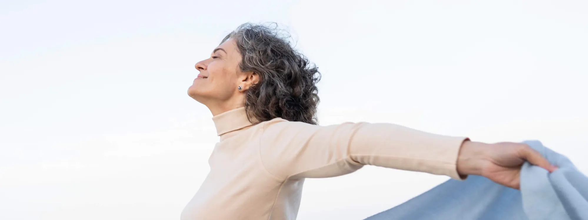 Frau streckt im Wind die Arme aus