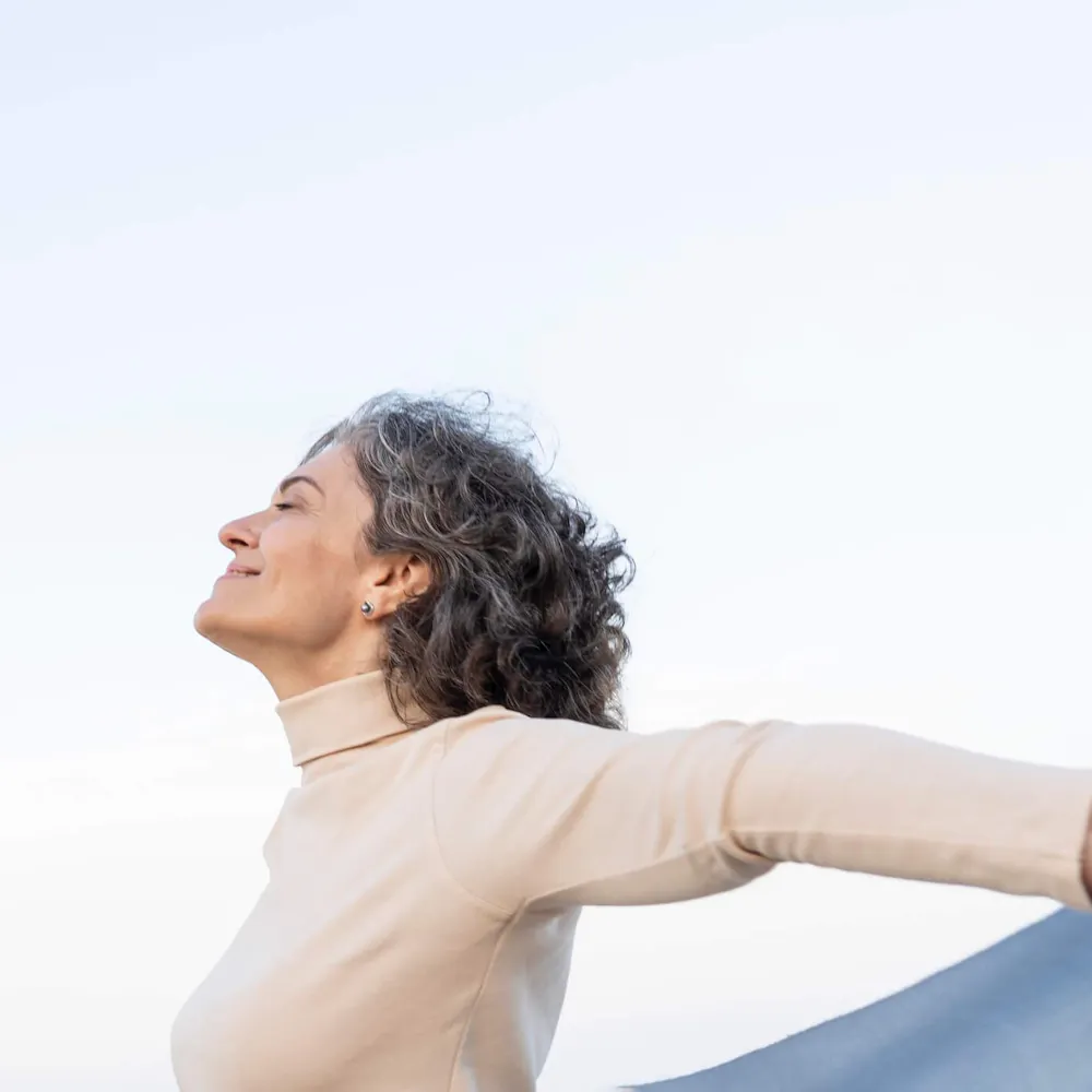Frau streckt im Wind die Arme aus