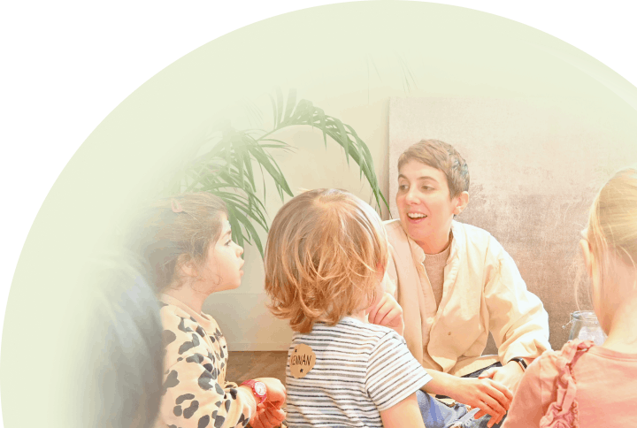 Little ones sitting on the floor, huddled around a teacher chatting