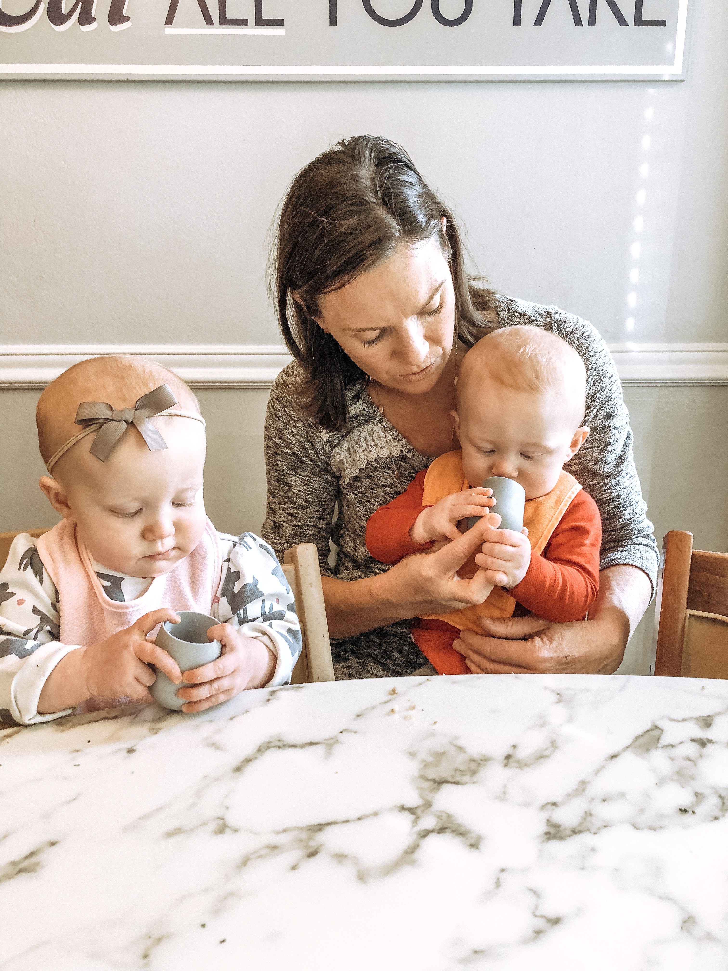 Twins learning how to drink out of an open cup