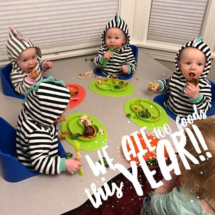 Four babies sitting at a feeding table with ezpz mini mats of food in front of them and text on the photograph that says "We ate 100 foods this year!!"