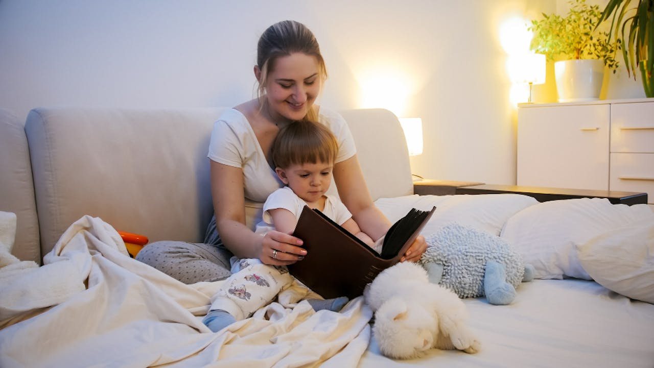 Mamá y niño de 2 años leyendo en la cama antes de ir a dormir