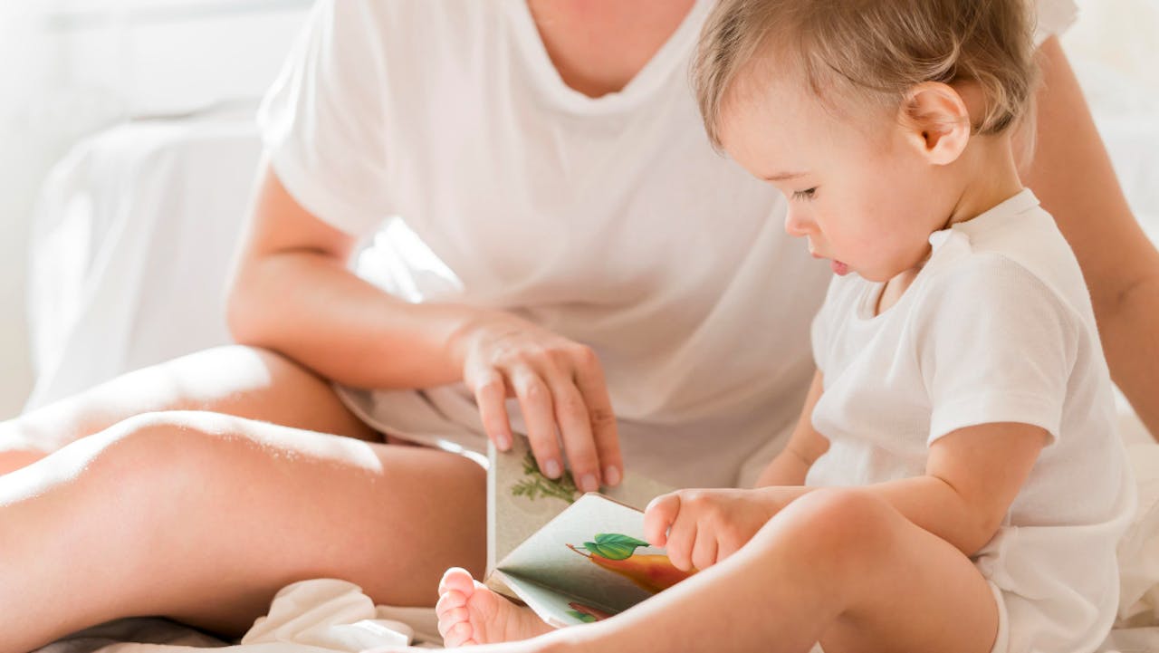 mamá y bebé jugando con un libro antes de irse a dormir