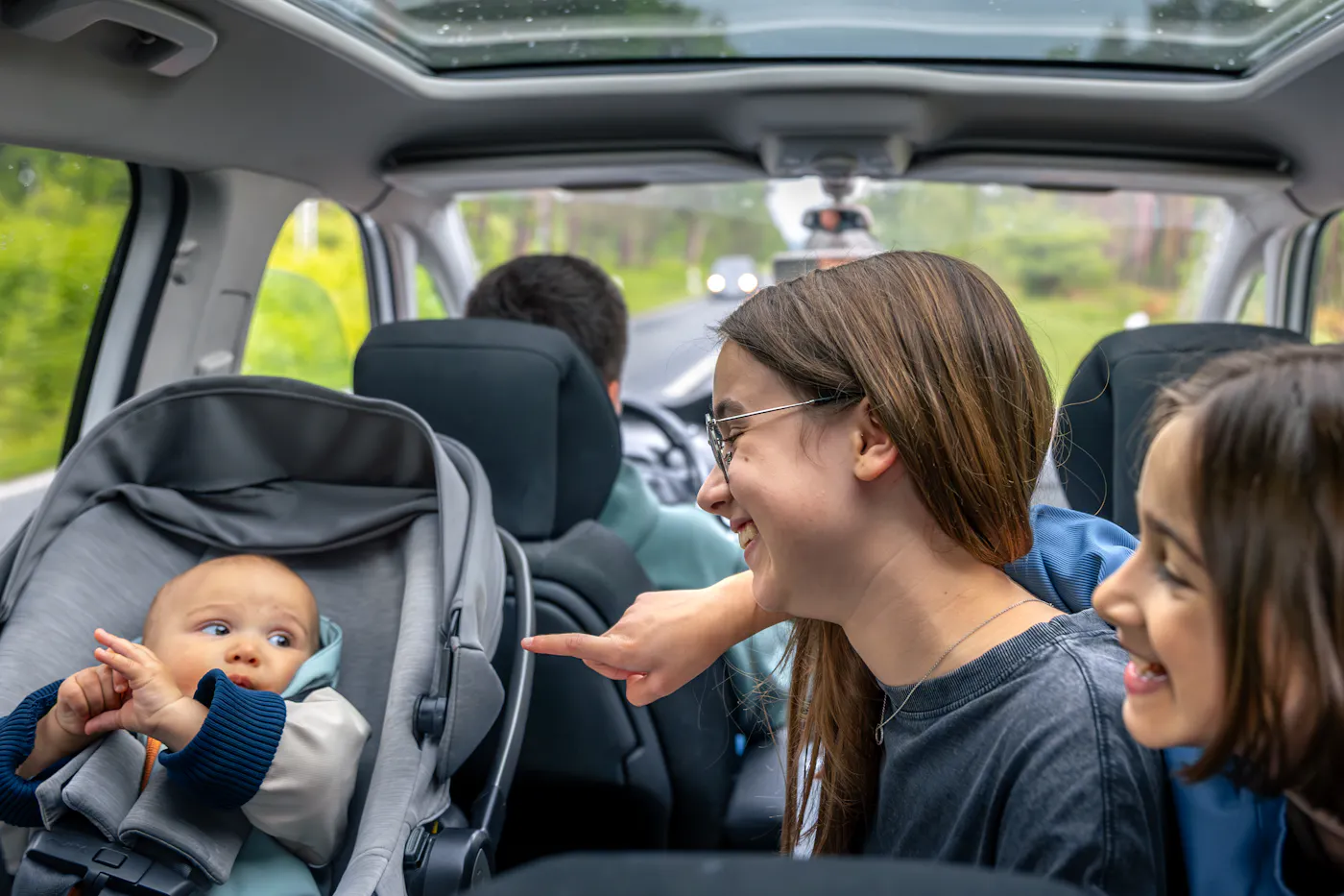 hermanos jugando y riendo con el bebe en el coche sin pantallas