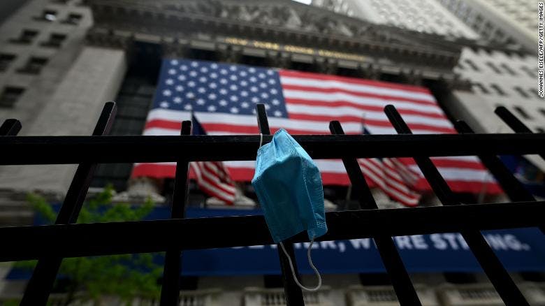 A face mask hangs on the gate in front of Wall Street