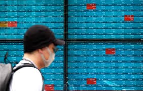 Person walks in front of stock market board