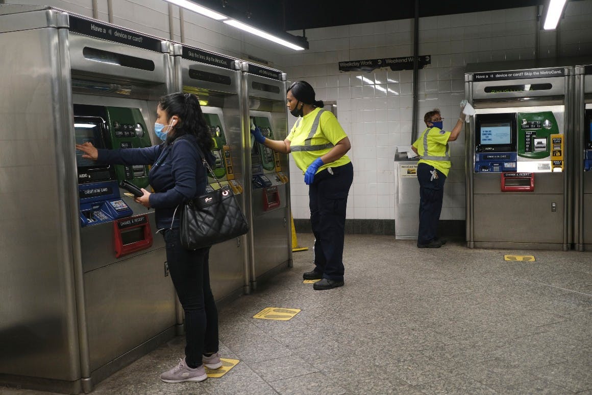 As a commuter buys a fare, MTA employees clean the machines in New York, Monday, June 8, 2020.