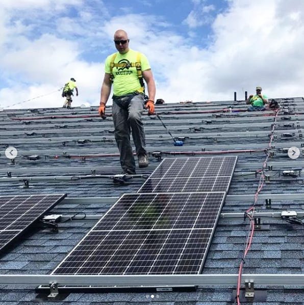 A ReVision Energy worker installs solar on the roof of Badger Balm in Gilsum, New Hampshire in May 2020.