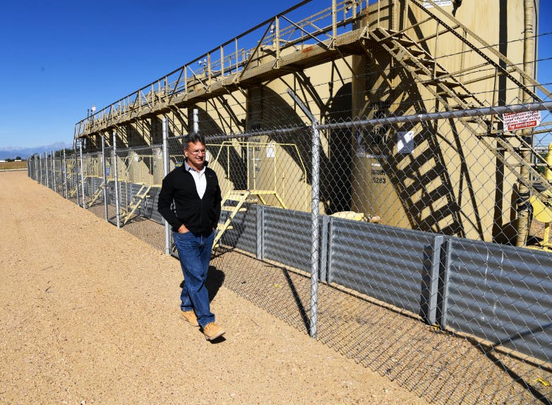 Farm owner Mark Schell walks next to tank batteries from a non-productive well on his 310-acre farm in Longmont on Sept. 02, 2020.