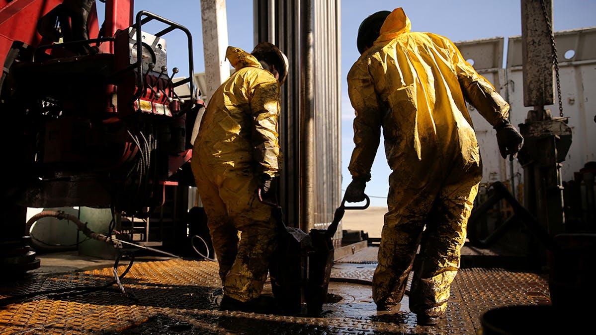 Two oil workers in safety gear on an oil rig