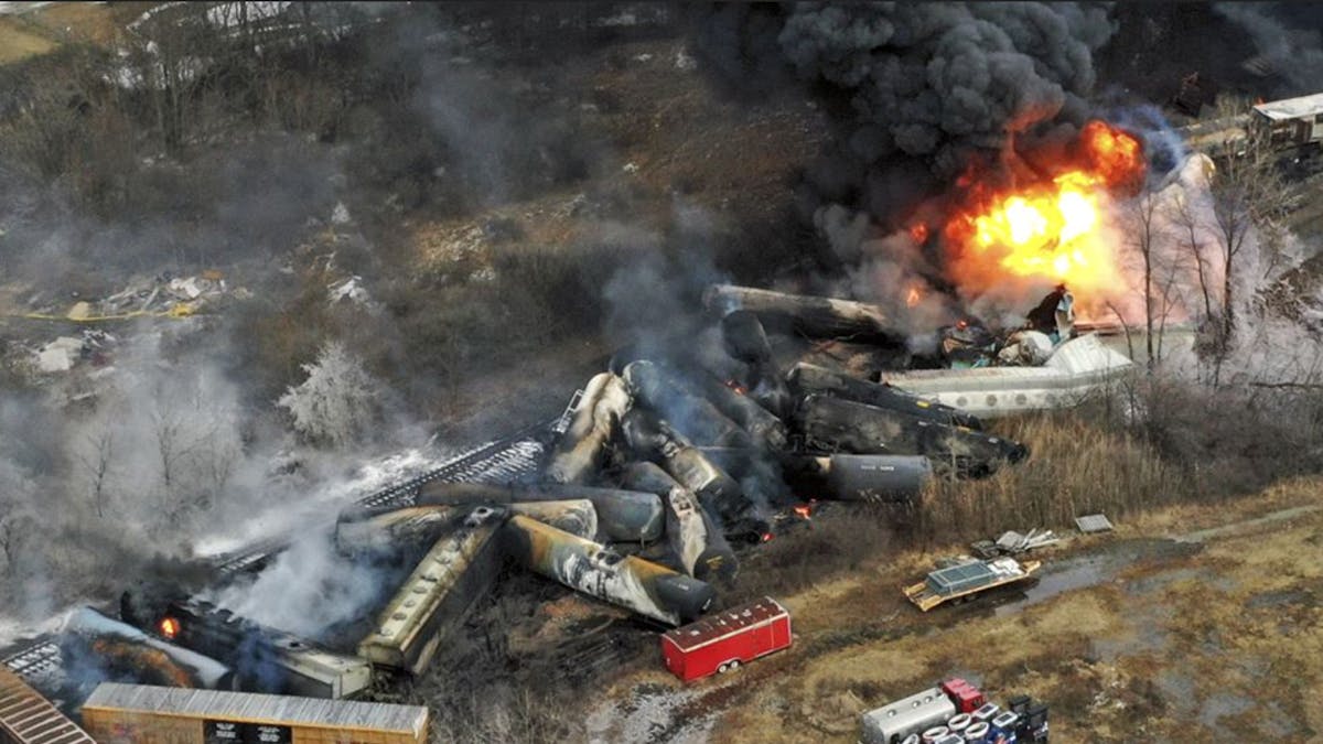 An aerial image of a derailed train. Parts of it are on fire and with black smoke billowing from it. 