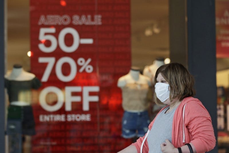 a woman walks past a store with sale signs displayed at Great Lakes Mall, in Mentor, Ohio
