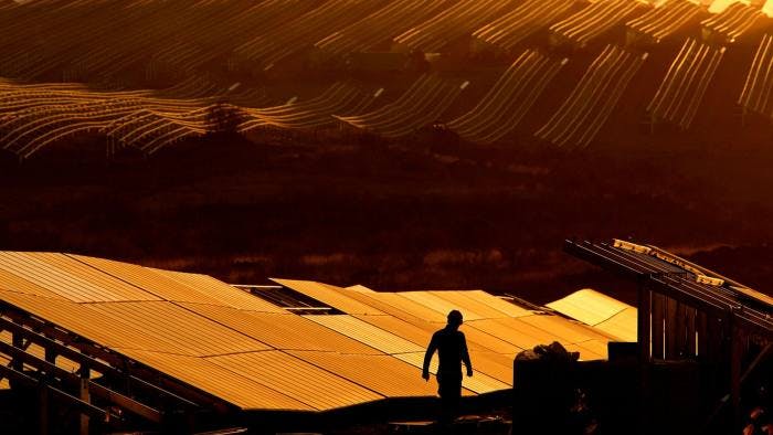 Worker walking solar panel field sunset