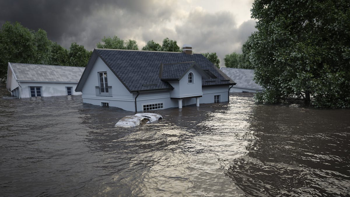 Exterior image of homes with flood waters nearly up to their gabled roofs.