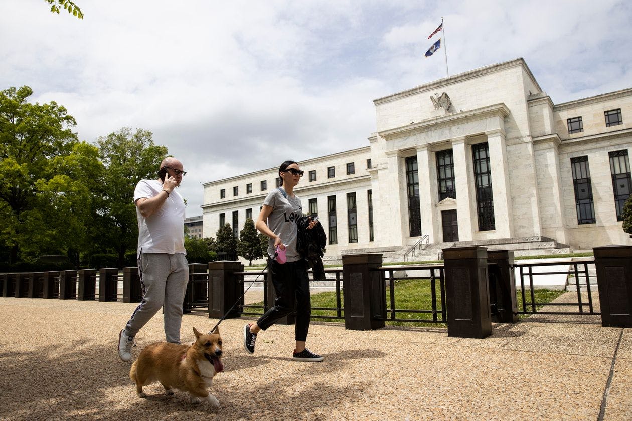 Two people walk past the Federal Reserve building