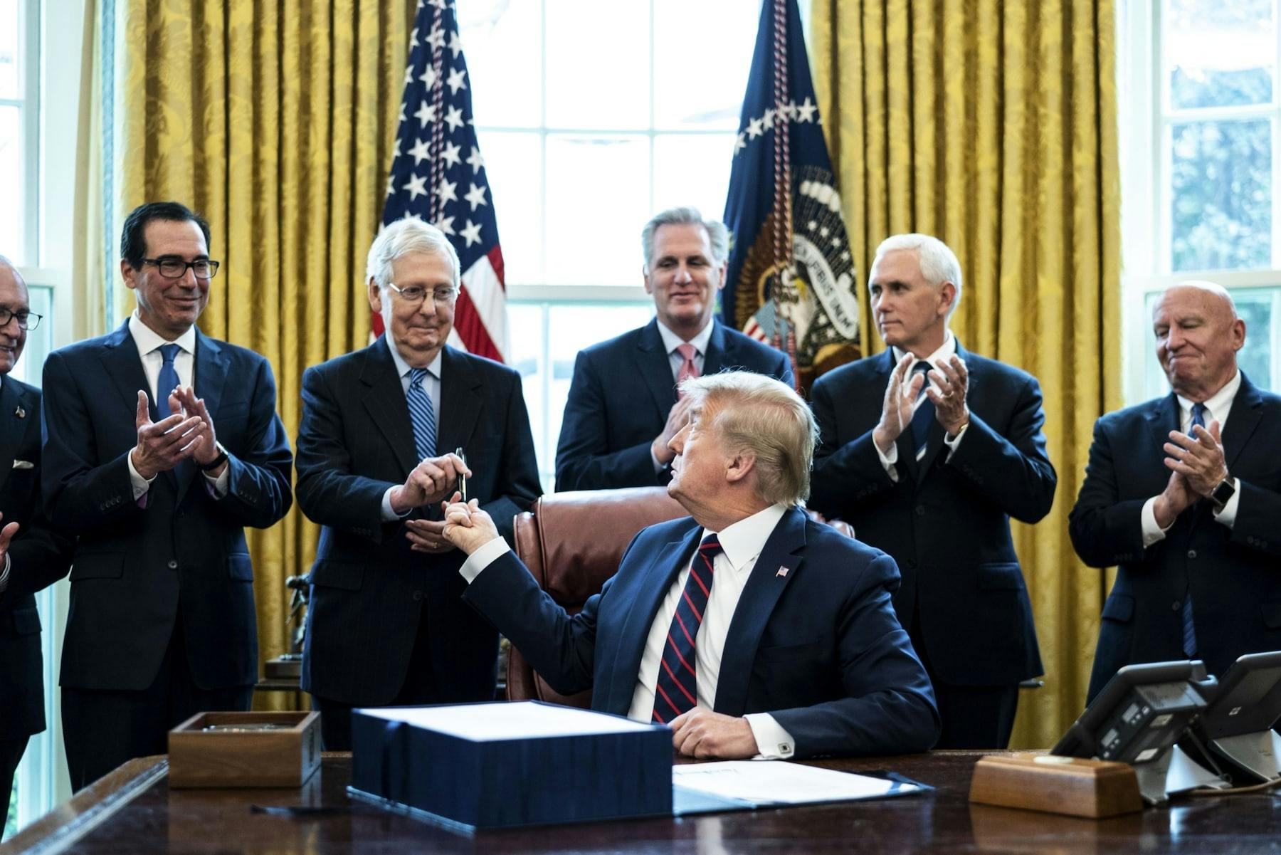 President Donald Trump hands a pen to Senate Majority Leader Mitch McConnell (R-Ky.) after signing the Cares Act on March 27.