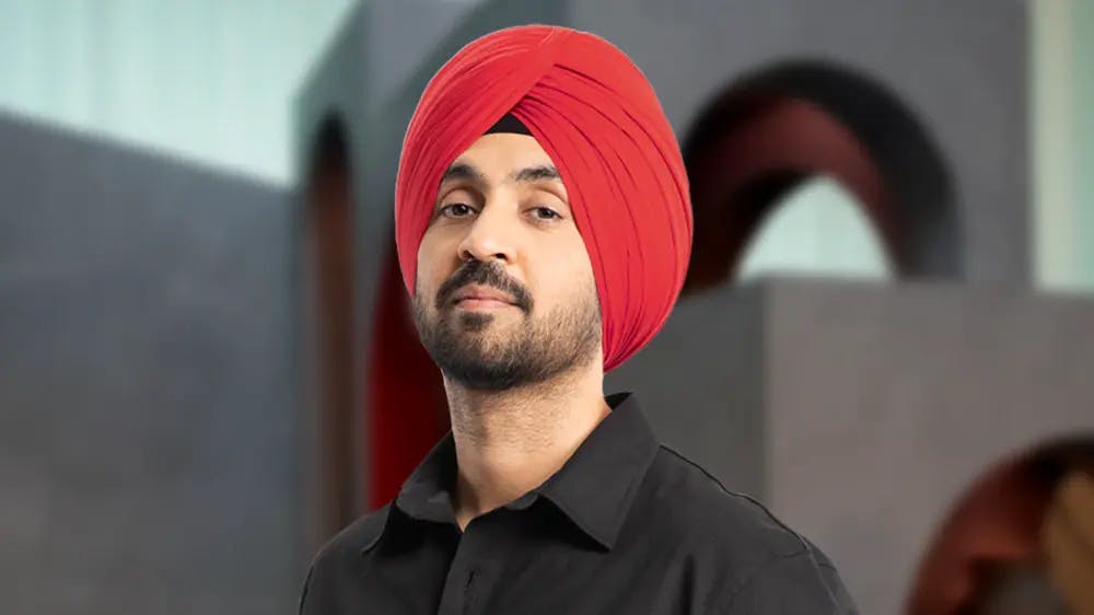 Featured photo of Diljit Dosanjh in red turban in dark grey shirt.