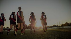 Women's collegiate rugby team walking together on a field at sunset