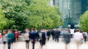 Business professionals walking around outdoor office space with trees