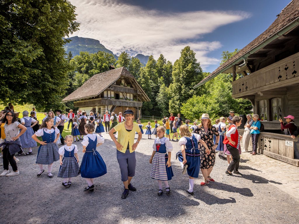 Trachten und Tänze: Besucherinnen und Besucher tanzen mit Kindern auf dem Ballenberg.