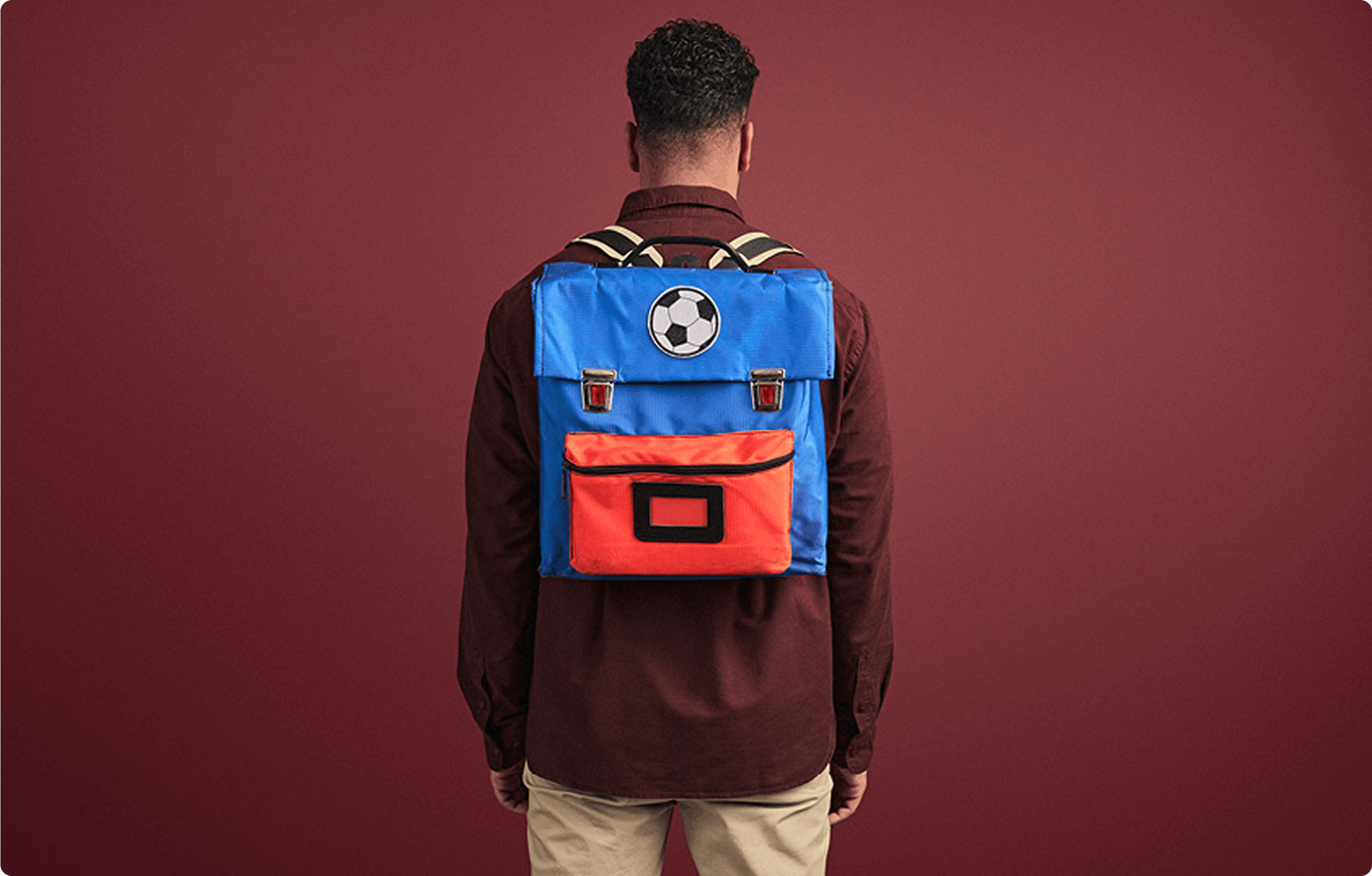 Ein Mann von hinten fotografiert, er trägt einen alten Schulranzen auf dem Rücken.