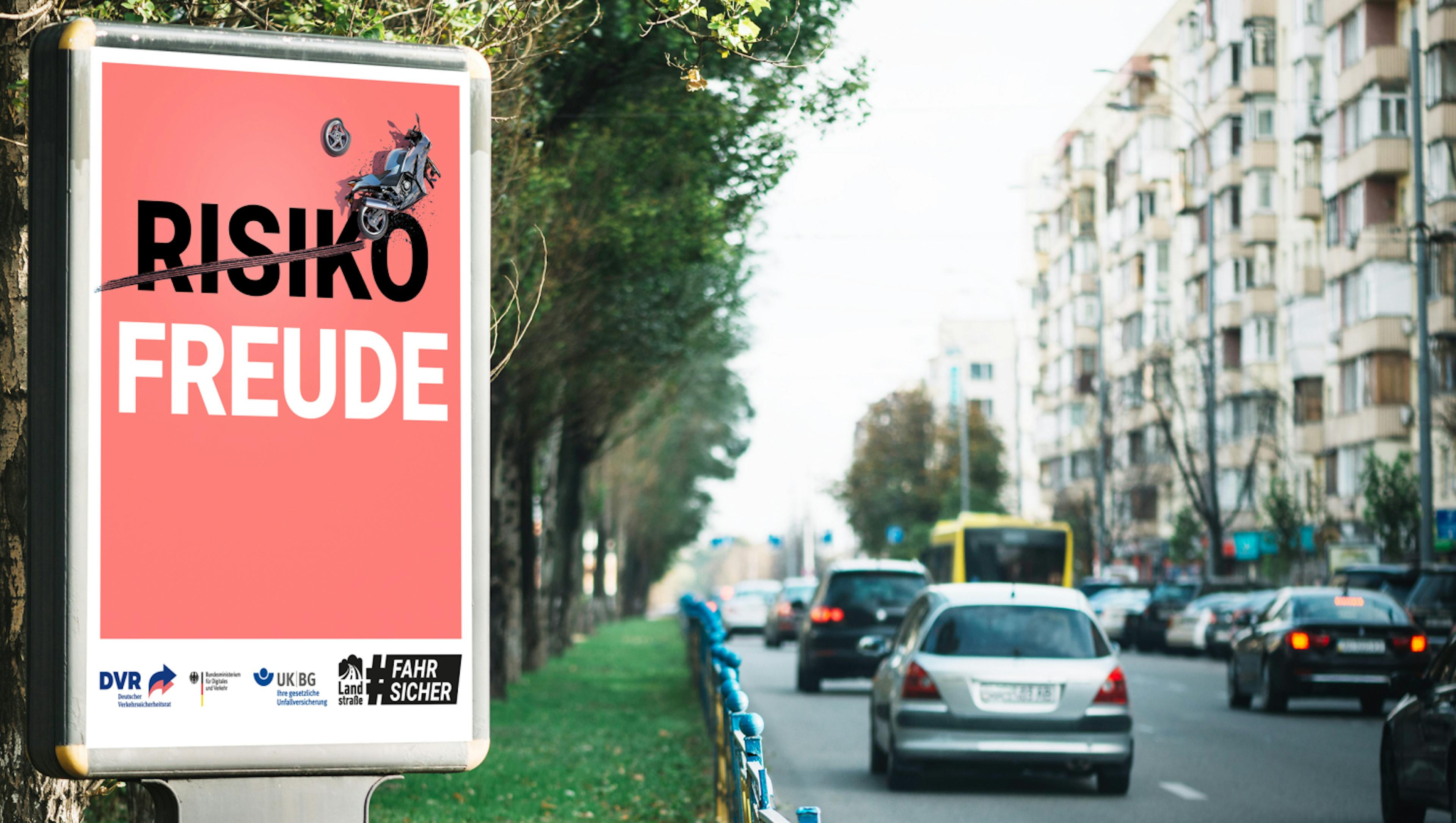 Ein Plakat an der Straße mit der Aufschrift "Risikofreude". Auf dem "Risiko" sind Bremsspuren, darüber liegt ein verunfalltes Motorrad.