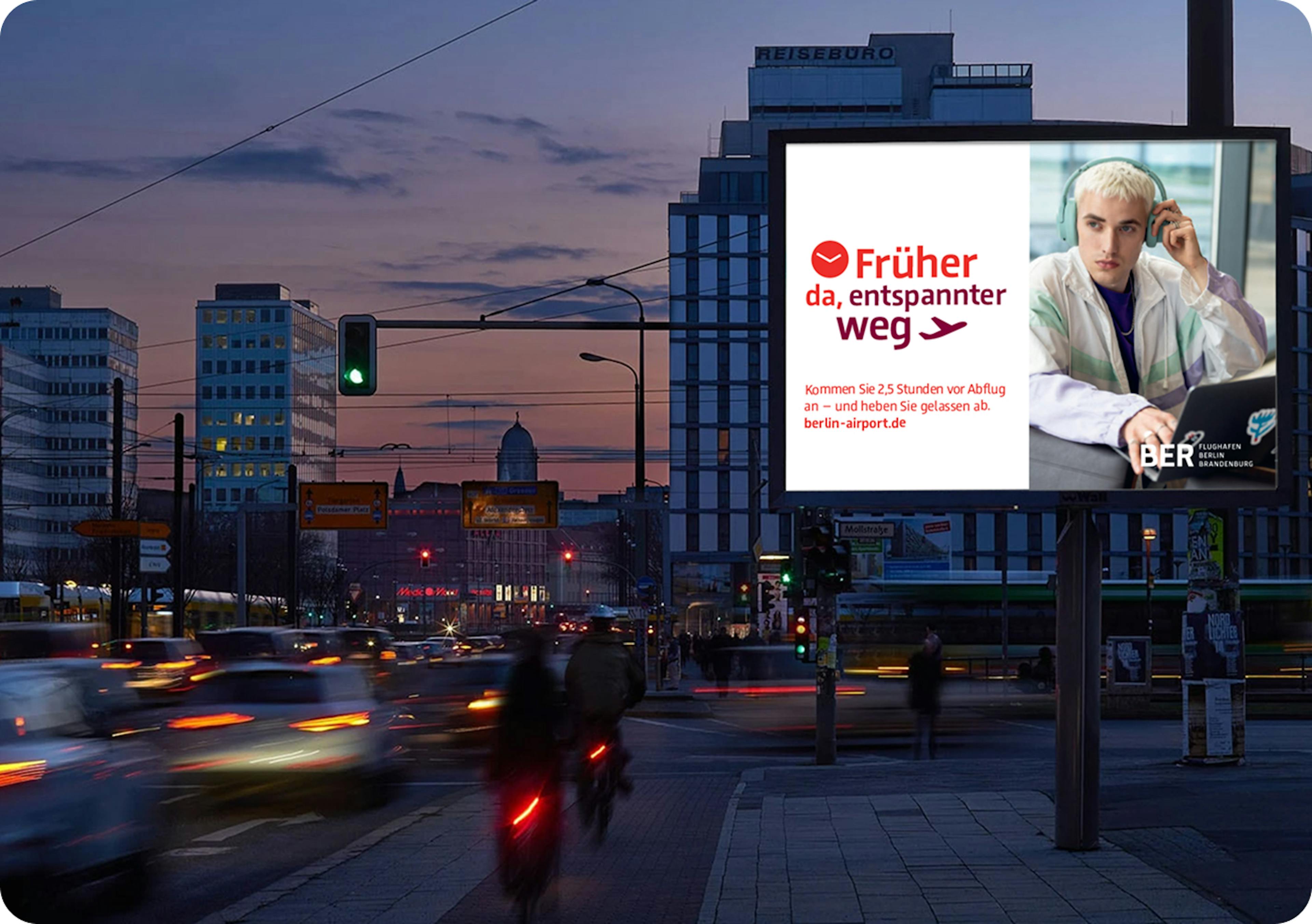 Plakat an einer Straße mit der Aufschrift "Früher da, entspannter weg", daneben ein Foto von einem Mann, der am Flughafen Musik hört.