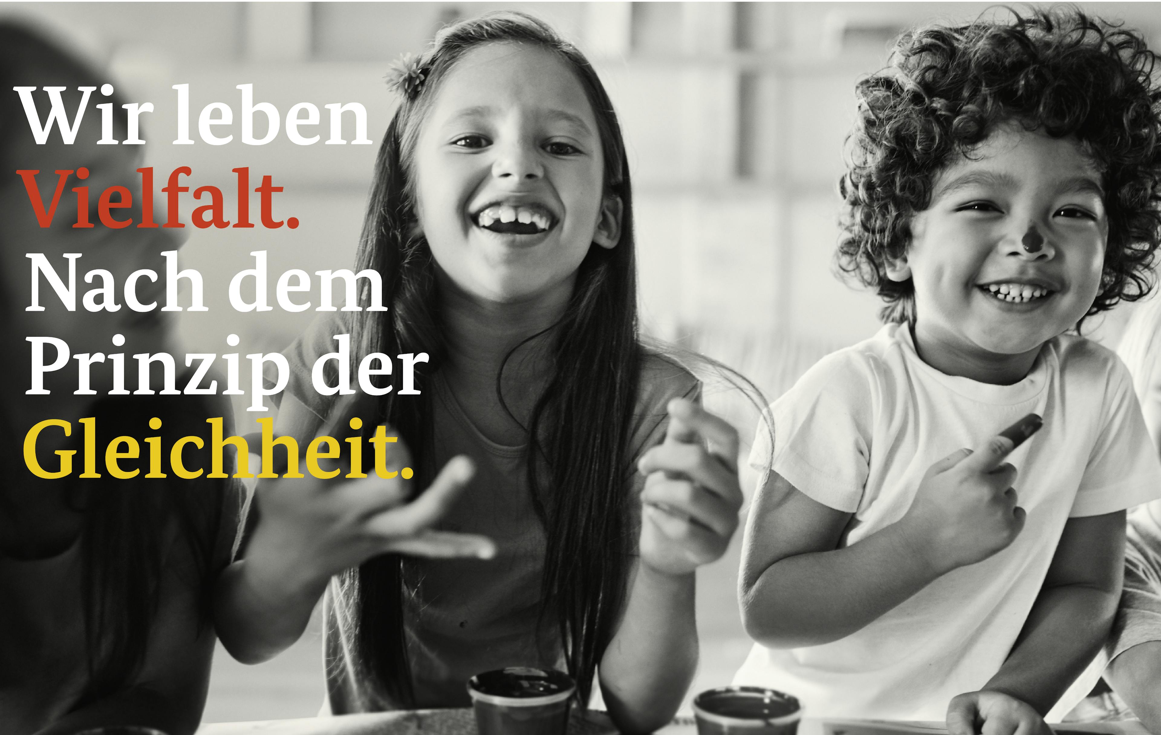 Schwarzweißbild von zwei lachenden Kindern, daneben Schriftzug "Wir leben Vielfalt. Nach dem Prinzip der Gleichheit."