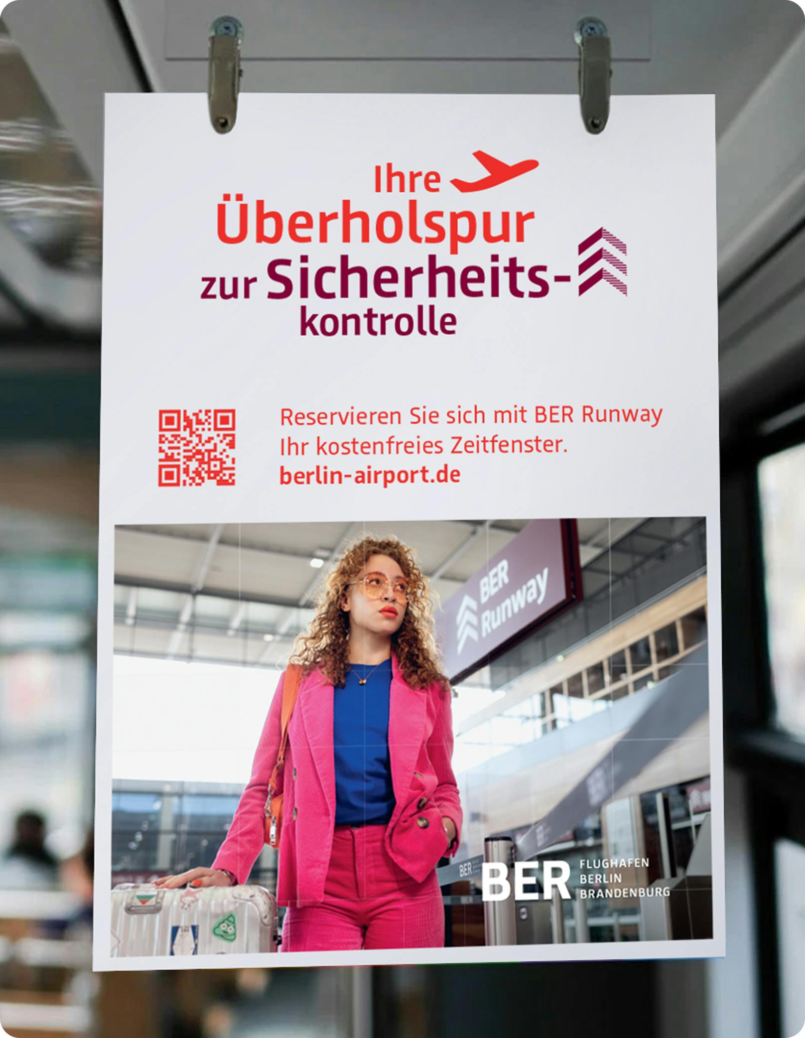 Ein Plakat mit der Aufschrift "Ihre Überholspur zur Sicherheitskontrolle" mit einem Flugzeug, darunter eine Frau am BER-Runway.