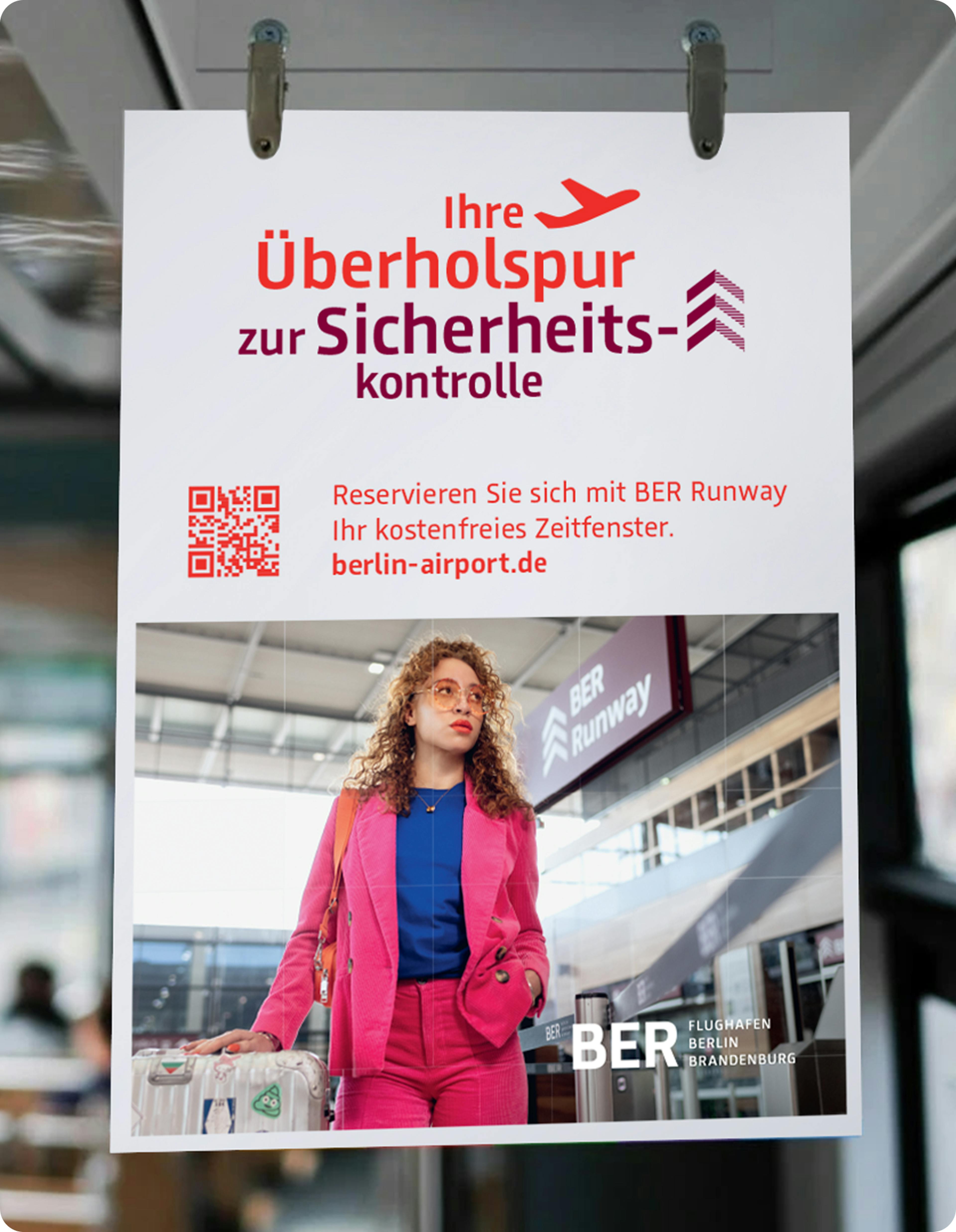 Ein Plakat mit der Aufschrift "Ihre Überholspur zur Sicherheitskontrolle" mit einem Flugzeug, darunter eine Frau am BER-Runway.