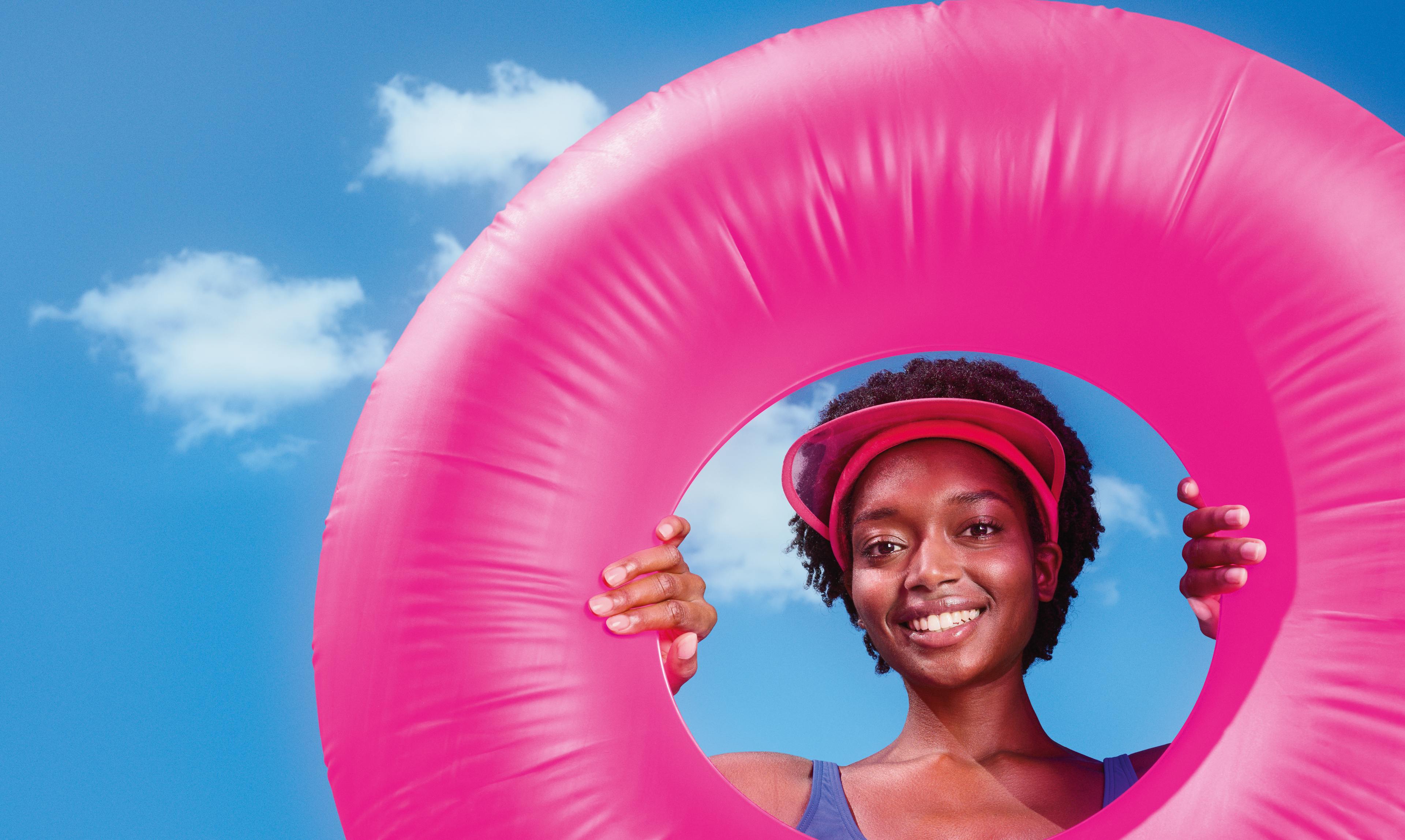 Eine Frau mit einem pinken Schwimmring vor blauem Himmel