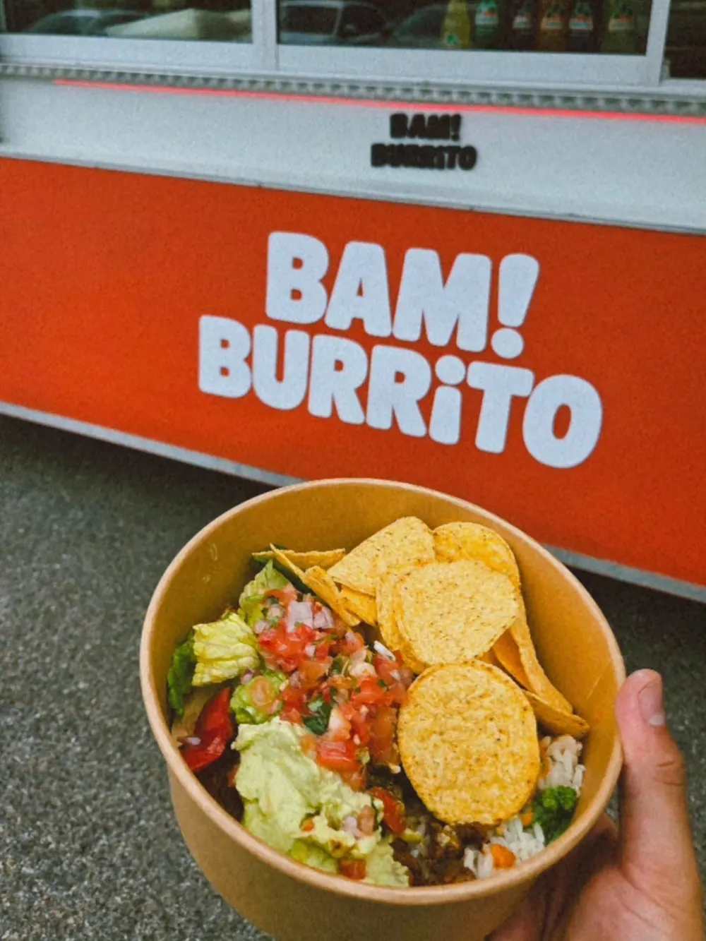 En bowl med nachochips hålls upp framför BAM! BURRITO-vagnen