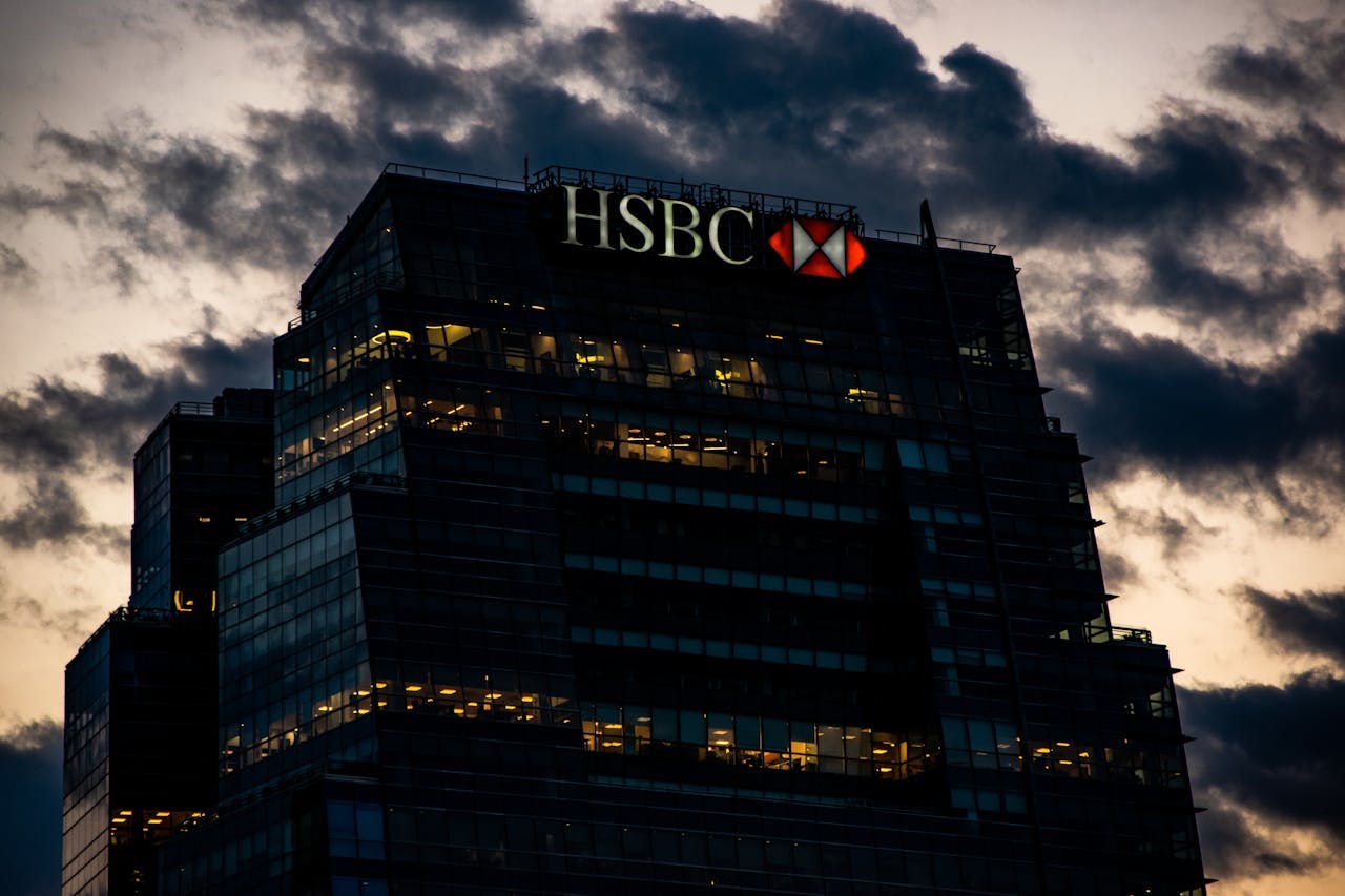 HSBC's logo on top of a bank tower with clouds behind, looking malevolent