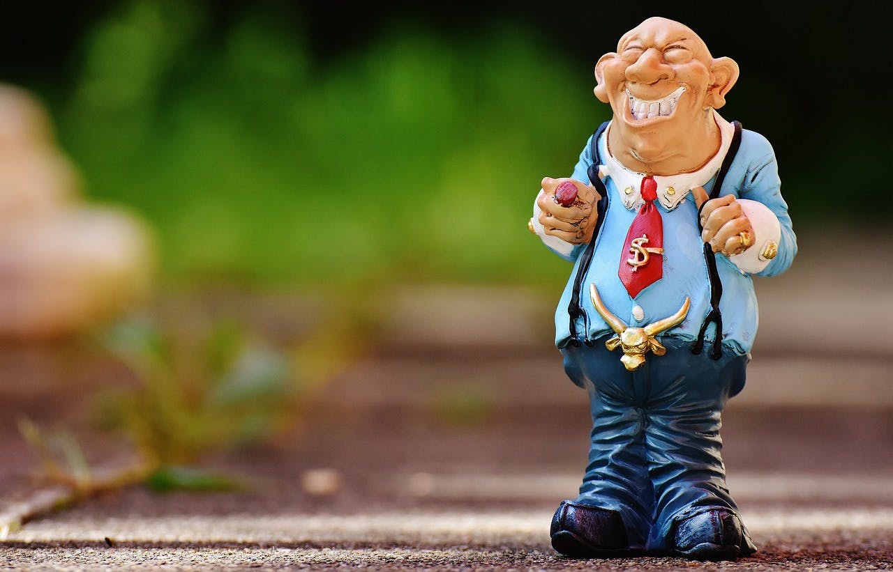 Image by Alexa from Pixabay. Sculpture of a businessman with a big smile, a cigar, a dollar sign tie clip and a belt buckle in the shape of a steer head