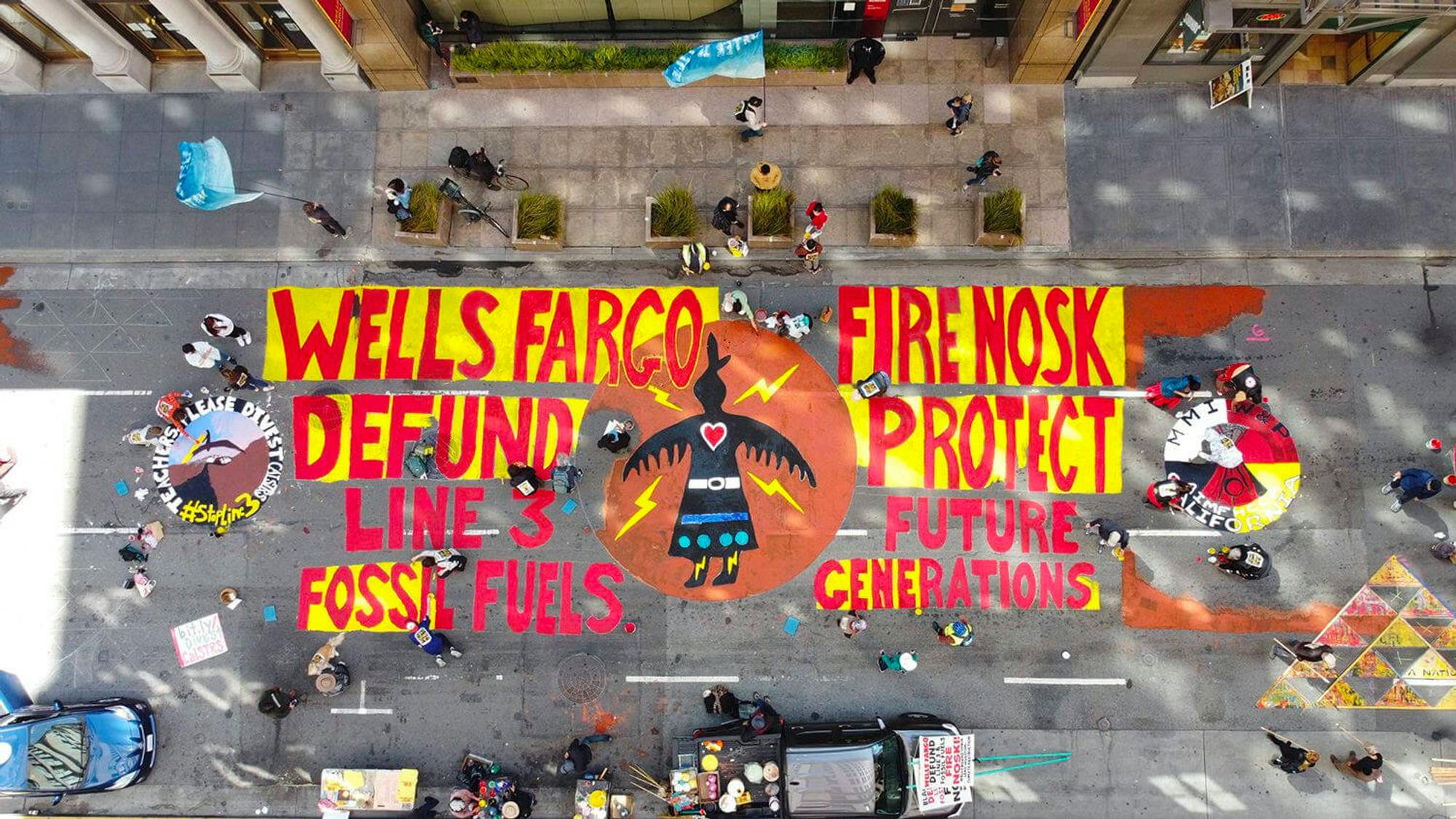Birds eye picture of protest showing "Wells Fargo, Fire Nosk, Defund Line 3 Fossil Fueles, Protect Future Generations"