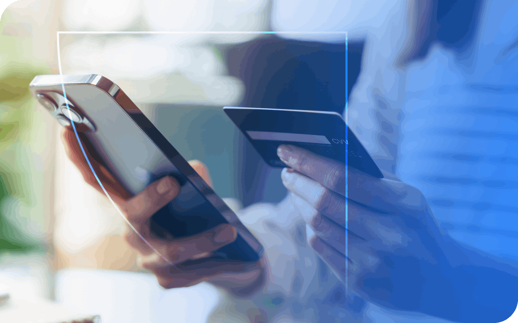 A close-up of hands, one holding a smartphone and the other holding a credit card