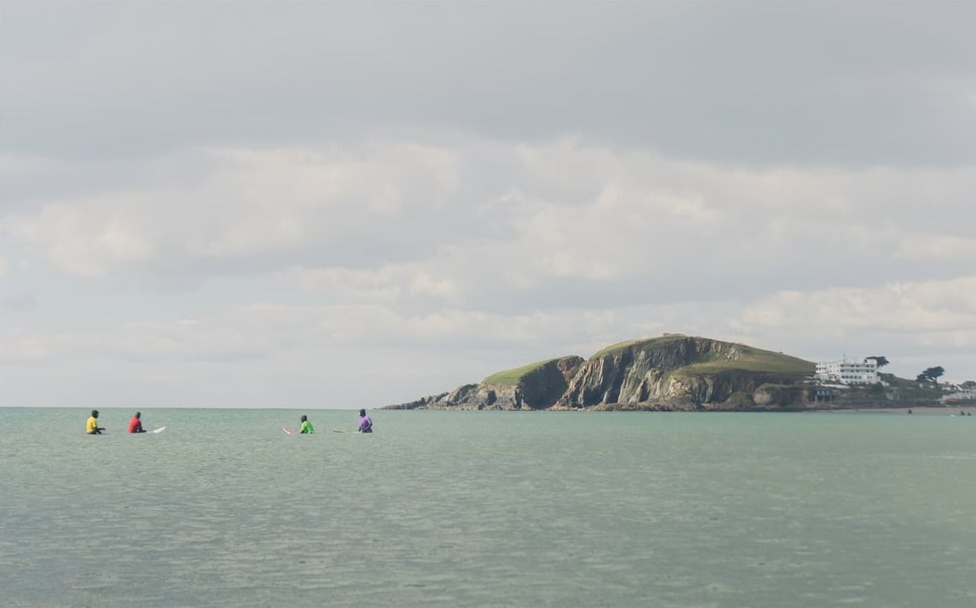 Surfing sitting in the water with Burgh Island in the background