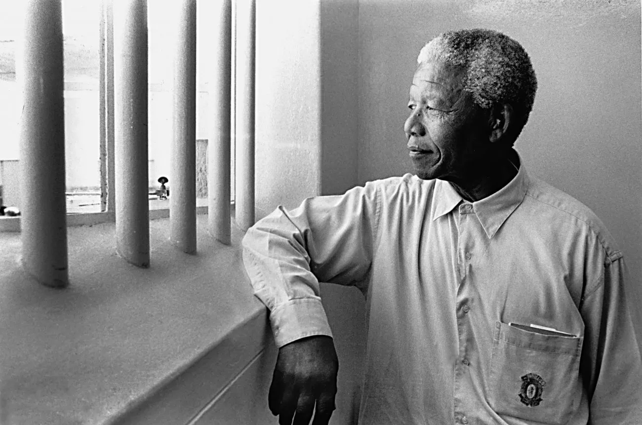 El Premio Nobel de la Paz posando en la celda de Robben Island (Sudáfrica) donde pasó 18 de sus 27 años de prisión (1994). Imagen vía: © Jürgen Schadeberg