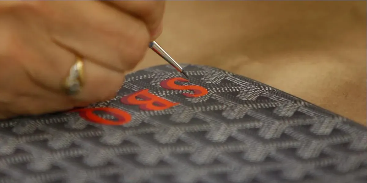 Die Goyard-Künstlerin Christine Mendez malt am Dienstag, den 19. März 2013 in San Francisco, Kalifornien, im Goyard-Atelier mit einer Lupe ein Monogramm auf eine Goyard-Handtasche (Foto von Lea Suzuki/The San Francisco Chronicle via Getty Images) (Detail)