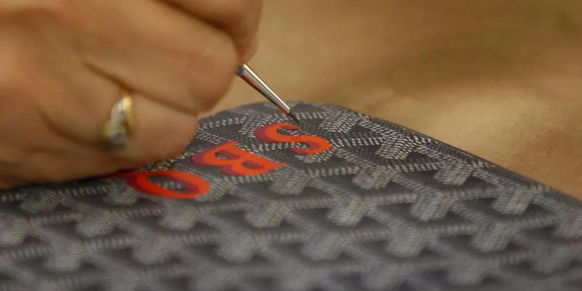 L'artiste Goyard Christine Mendez utilise une loupe alors qu'elle peint un monogramme sur un sac à main Goyard à l'atelier Goyard le mardi 19 mars 2013 à San Francisco, Californie. Photo par Lea Suzuki/The San Francisco Chronicle via Getty Images (détail)