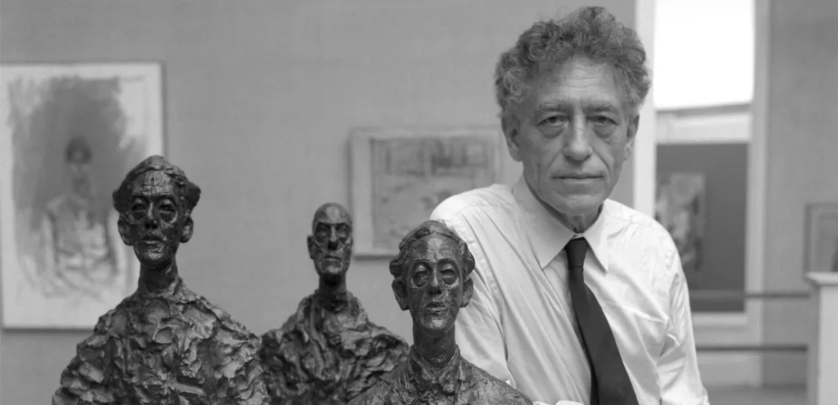 Lo scultore svizzero Alberto Giacometti, con indosso una camicia bianca e una cravatta scura, presenta tre delle sue sculture alla 31a Mostra della Biennale d'arte a Venezia, 1962. (Foto di Archivio Cameraphoto Epoche / Getty Images)