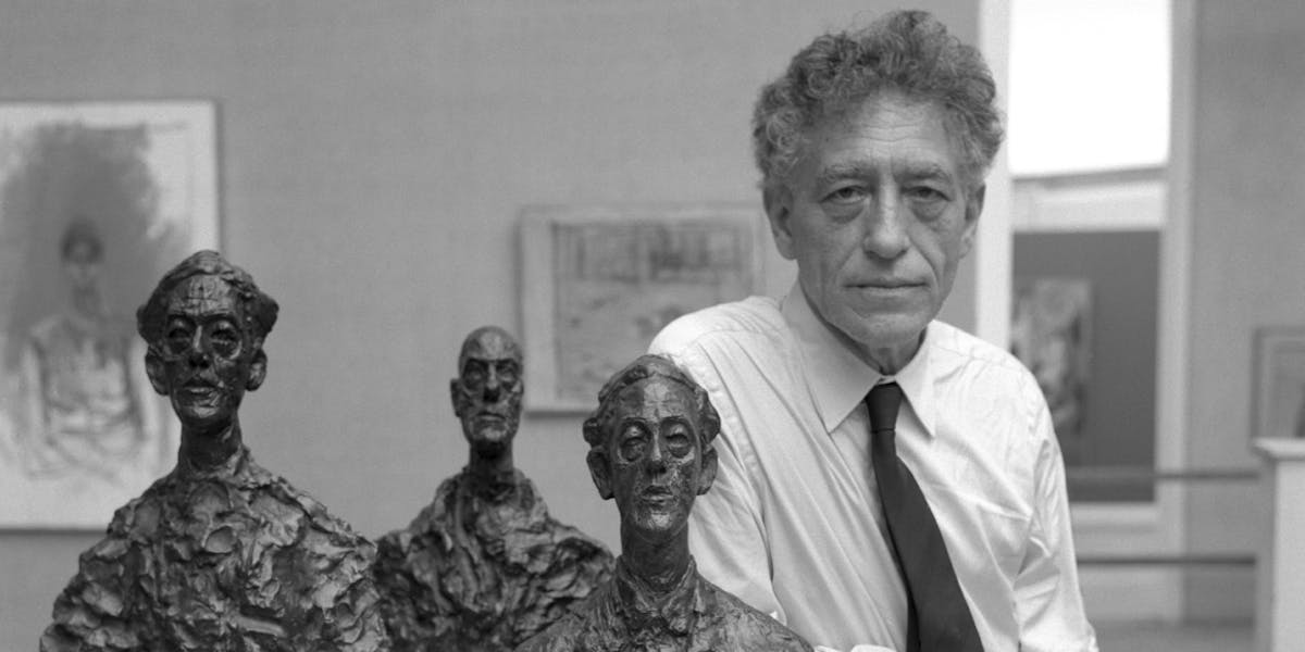 Lo scultore svizzero Alberto Giacometti, con indosso una camicia bianca e una cravatta scura, presenta tre delle sue sculture alla 31a Mostra della Biennale d'arte a Venezia, 1962. (Foto di Archivio Cameraphoto Epoche / Getty Images)
